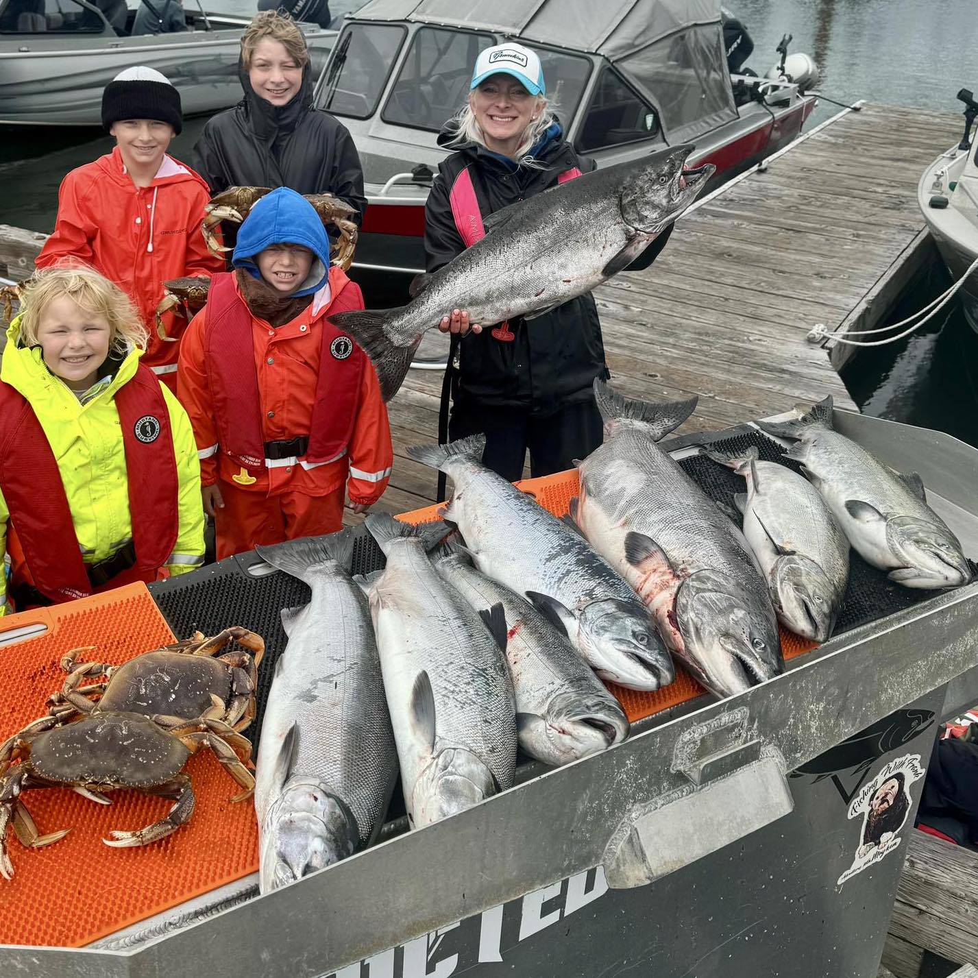 Family posing on the dock with a haul of freshly caught Chinook salmon and Dungeness crab after a successful guided combo trip in Oregon—Adventures with Mayhem Outfitters Fishing and Cabbing guided trip